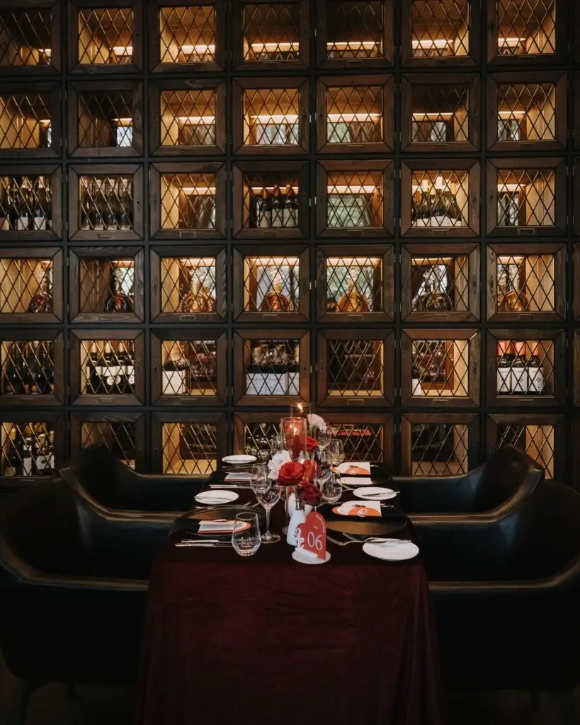 Intimate wedding reception table with red floral décor beneath Acquafarina’s framed art wall