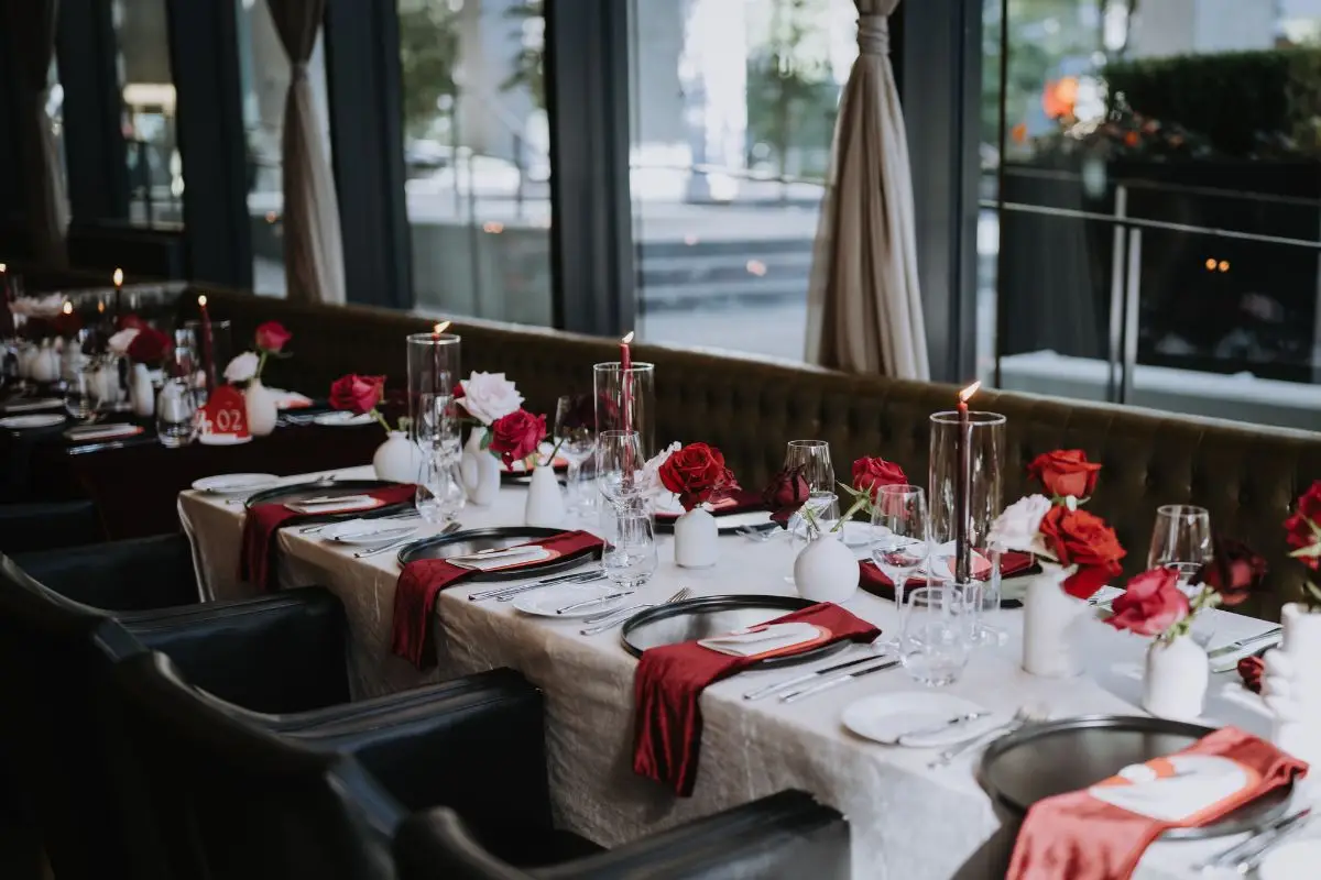 Elegant wedding reception table with red roses and place settings at Acquafarina in Vancouver