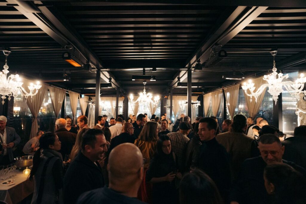 Guests mingling at an evening private reception beneath chandeliers at Acquafarina in Vancouver