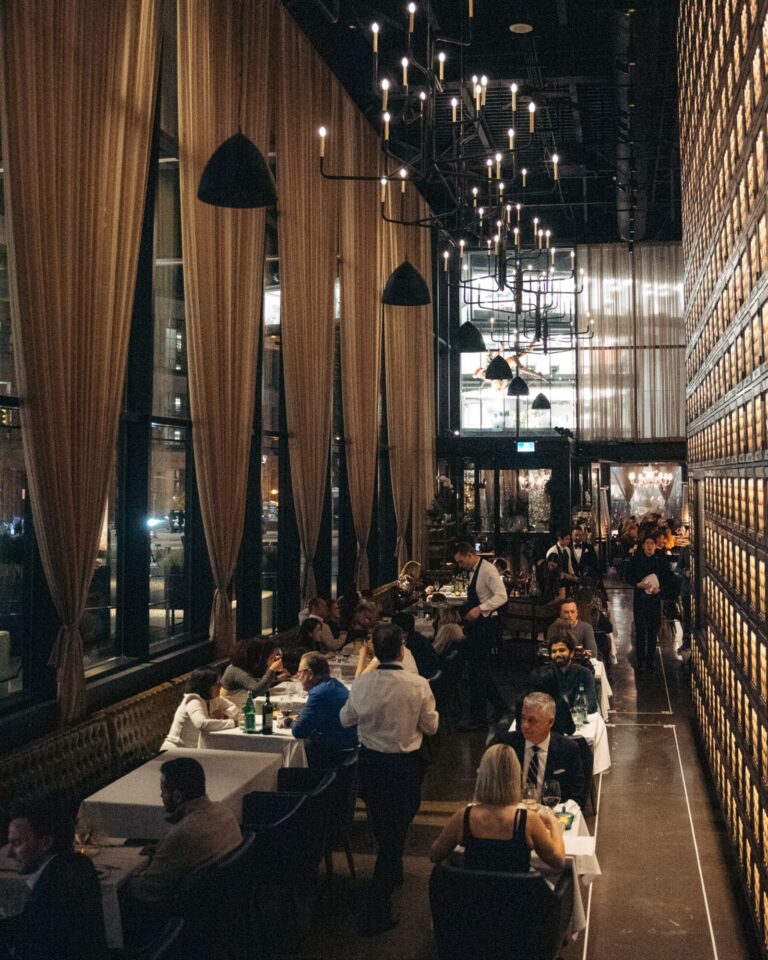 Guests dining beneath floor-to-ceiling curtains in Acquafarina’s main dining room in Vancouver