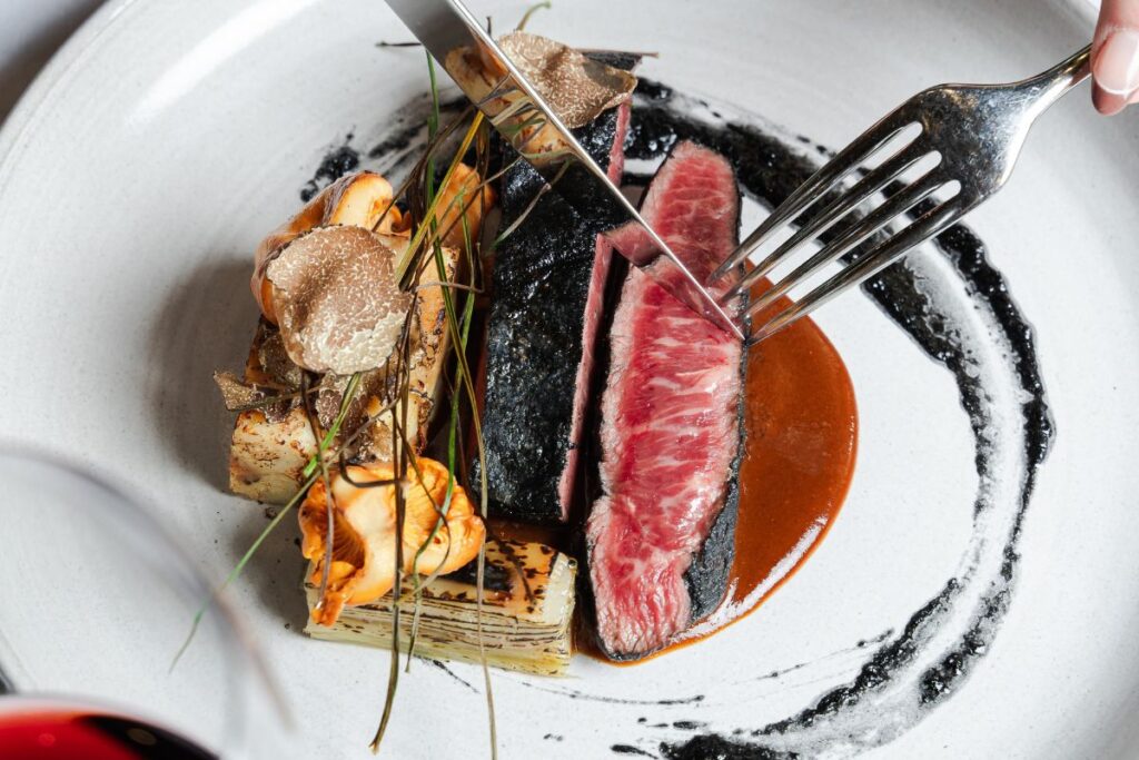 Sliced steak with seasonal accompaniments plated for dinner at Acquafarina in Vancouver